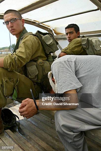 Israeli soldiers guard an unidentified handcuffed and blindfolded Palestinian from the Jenin district of the West Bank August 6, 2003 outside the...