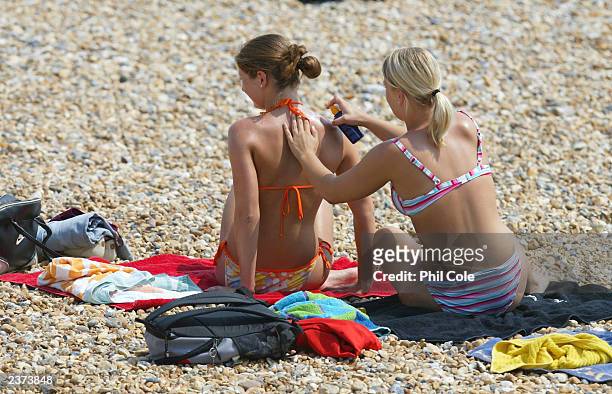 Young woman places suncream on her friend while the sunbath on the beach during a heatwave August 6, 2003 in Eastbourne, England. Temperatures in the...