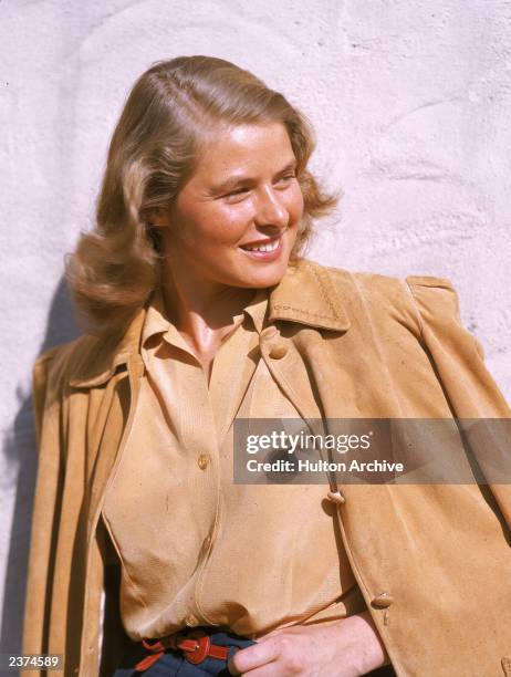 Swedish-born actor Ingrid Bergman smiles as she poses outdoors, wearing a tan leather jacket, circa 1945.