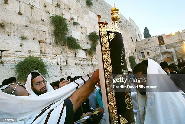 Religious Jews pray at dawn with a Torah scroll at the Western Wall in Jerusalem's Old City during the annual 9th of Av memorial for the destruction...