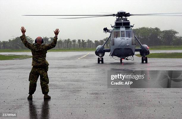 Royal Australian Navy Sea King helicopter arrives amid heavy downpours at Honiara airport to fly Australian officials and soldiers to the troubled...