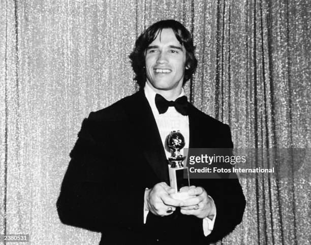 Austrian bodybuilder and actor Arnold Schwarzenegger posing with his award for Most Promising Newcomer to Films for the film, "Stay Hungry," at the...