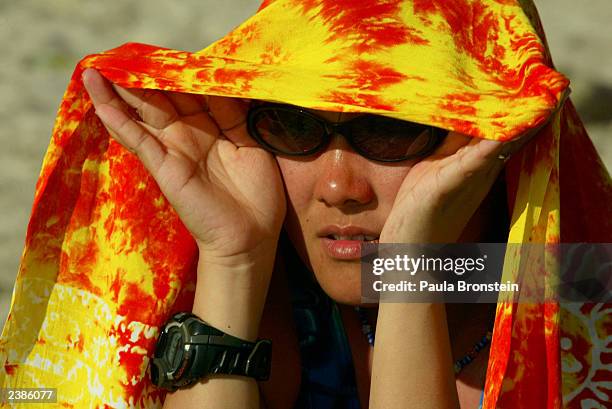 Japanese tourist covers herself from the sun after getting sunburnt on Kuta beach August 10, 2003 in Bali, Indonesia. Bali depends on tourism which...