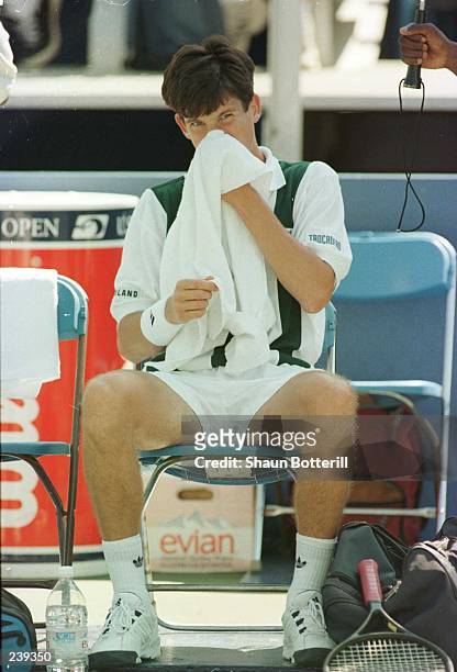 Tim Henman of Great Britain wipes the sweat from his face while relaxing during a break in the action of his match with Doug Flach of the USA in the...