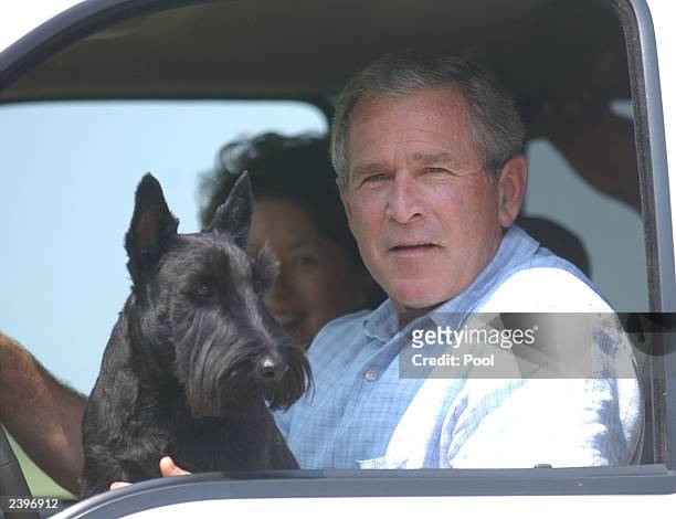 President George W. Bush sits in his vehicle as his dog, Barney, sits on his lap near his ranch August 13, 2003 in Crawford, Texas. President Bush...