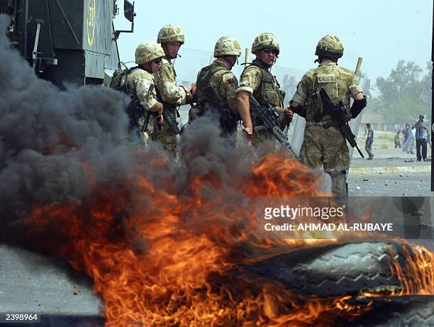 British soldiers stand by burning tires as clashes broke out between Iraqis and British troops in the southern city of Basra 09 August 2003 over fuel...