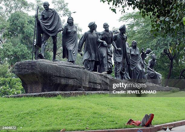 An Indian women takes a break from cleaning a statue which commemerates the Salt March of 1930 and features Indian leader Mahatma Gandhi leading a...