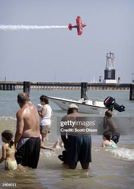 The Oracle Challenger stunt plane flies over spectators watching from the beach at the 45th annual Chicago Air and Water Show August 17, 2003 in...