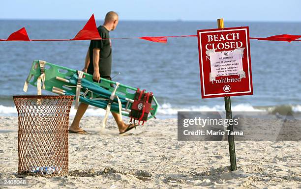 Lifeguard walks past a "Beach Closed" sign at Coney Island August 18, 2003 in New York City. New York City beaches were closed by the health...