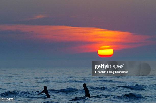 Couple swims in the sea at sunset off the beach of Yalta August 18, 2003 in Crimea, Ukraine. After the number of annual visitors to the Black Sea...