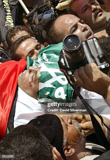 Palestinians give their friend and colleague, cameraman Mazen Dana, a martyr's funeral August 20, 2003 in the West Bank town of Hebron. Dana, a...