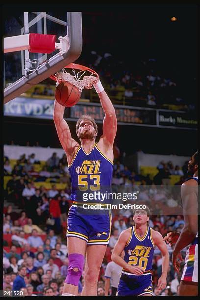 Center Mark Eaton of the Utah Jazz slam dunks as teammate guard Bobby Hansen looks on during a game against the Denver Nuggets at McNichols Arena in...