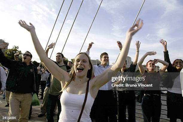 Crowd of people stand on Hungerford foot bridge waving and cheering at passing boats and trains as they participate in a "flash mob" on August 21,...