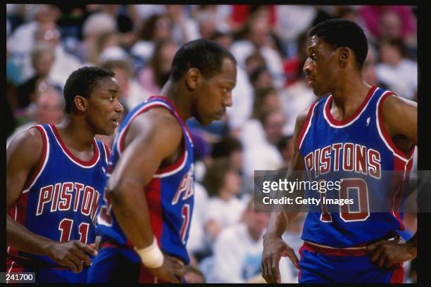 Guard Isiah Thomas, left, forward Dennis Rodman, right, and forward Vinnie Johnson of the Detroit Pistons talk to each other during a game. Mandatory...