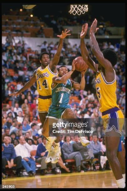Guard Tyrone Bogues of the Charlotte Hornets goes up for two between guard David Rivers and forward A. K. Green of the Los Angeles Lakers during a...