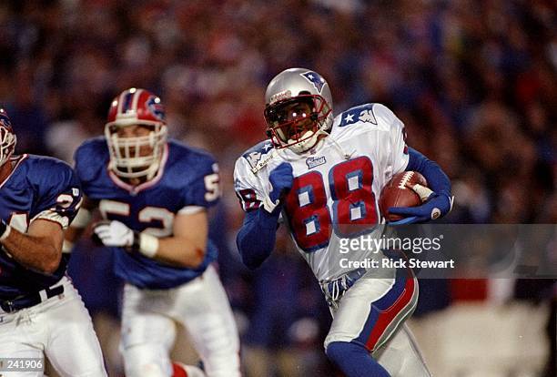 Running back Terry Glenn of the New England Patriots runs with the ball as linebacker John Holecek of the Buffalo Bills chases him during a game at...