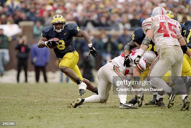 Tailback Chris Howard of the Michigan Wolverines runs with the ball as linebacker Andy Katzenmoyer of the Ohio State Buckeyes runs toward him during...