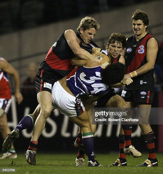 Mark Bolton and Mark McVeigh of the Bombers wrestle with Paul Medhurst of the Dockers during the round 21 AFL match between the Essendon Bombers and...