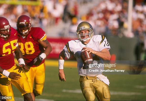 Quarterback Cade McNown of the UCLA Bruins scrambles with the ball and is chased by defensive end George Perry of the USC Trojans during a game at...