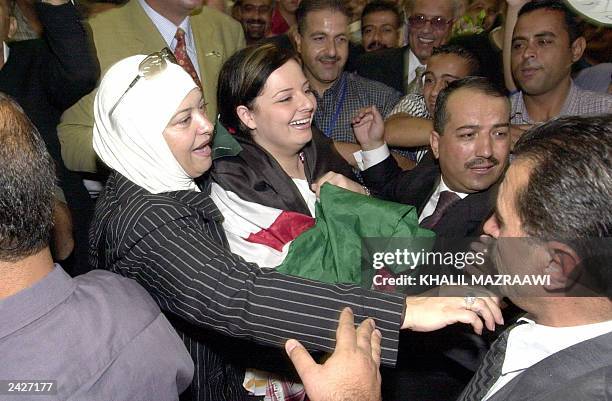 Arab's Super Star Diana Karazon of Jordan, wrapped in the national flag, is escorted by a female relative as she is greeted by fans upon her arrival...