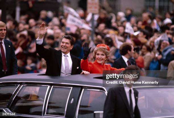 President Ronald Reagan and wife Nancy wave to the crowd from the Presidential Limosine as they ride down Pennsylvania Avenue during the Inaugural...