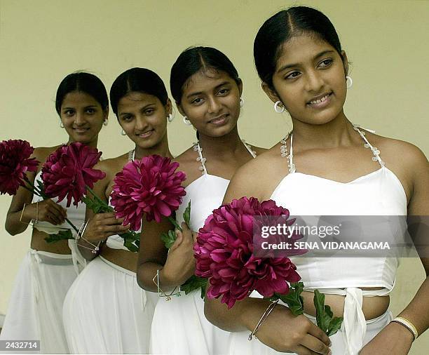 Two pairs of Sri Lankan twins Rasikala Gayathri Wathsala Rasangi Thanuja Damayanthi and Thamara Damayanthi hold flowers as they pose during a pageant...