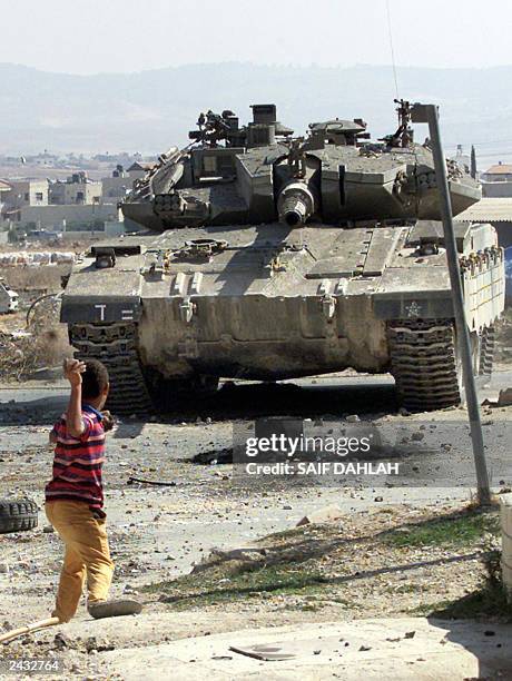 Palestinian boy throws a stone at an Israeli tank, 23 Auguast 2003, in the West Bank city of Jenin. The Palestinian leadership blamed Israeli Prime...