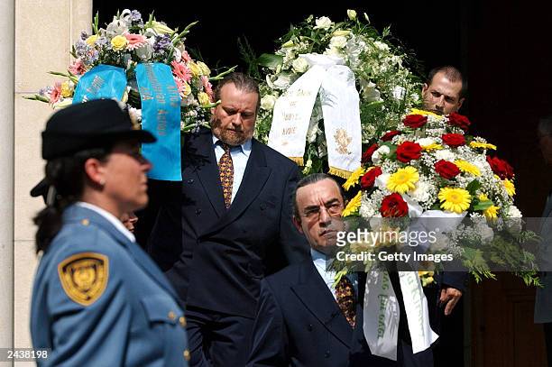 Undentified people carry flowers in front of UN security staff after the funeral ceremony for UN special envoy to Iraq, Sergio Vieira de Mello, at...