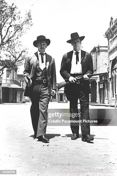 Kirk Douglas as Dr. John 'Doc' Holliday and Burt Lancaster and Marshal Wyatt Earp walk toward camera carrying guns in a film still from the 1957 film...