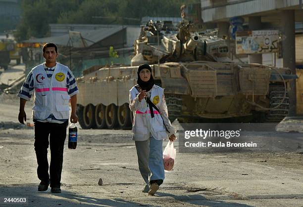 Palestinian Emergency rescue workers walk by an Israeli tank parked inside Balata refugee camp after clashes August 28 2003 in the West Bank city of...