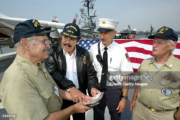 Workers prepare a 25 foot American flag in the background as singer/songwriter Tony Orlando jokes with World War 2 navy veteran Morton Simmons, from...