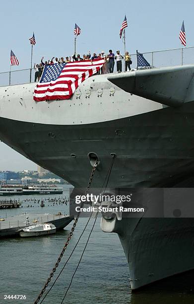 Workers aboard the Intrepid Sea-Air-Space Museum join singer/songwriter Tony Orlando and World War 2 veterans in draping a 25 foot flag over the bow...