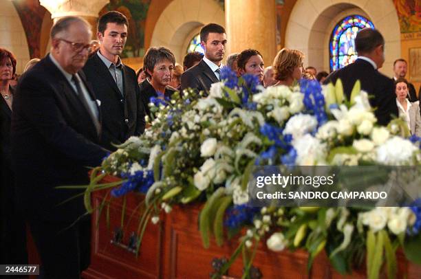 Adrian and Laurent de Mello stand between their mother, Annie and wife of Sergio Vieira de Mello as they look at the coffin containing containing his...