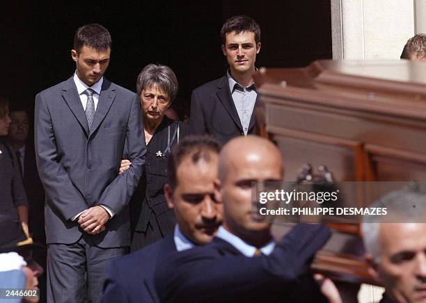 Adrian and Laurent de Mello stand between their mother, Annie and wife of Sergio Vieira de Mello as they follow the coffin containing his body after...