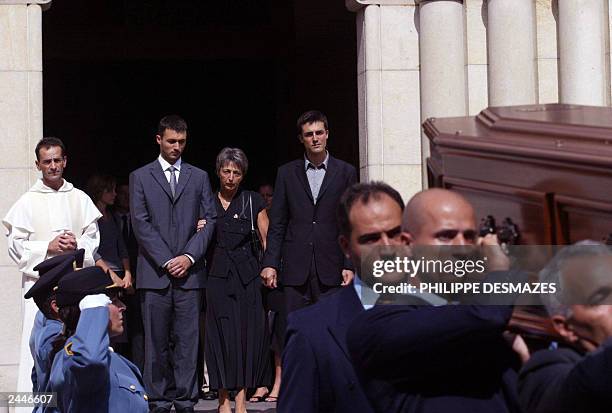 Adrian and Laurent de Mello stand between their mother, Annie and wife of Sergio Vieira de Mello, UN special envoy to Iraq as they follow the coffin...