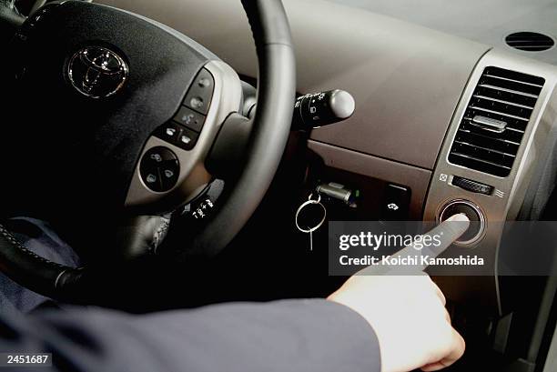 Member of the press touches the ignition button of the Toyota Prius Hybrid car at a press conference September 1, 2003 in Tokyo, Japan. Toyota unveil...