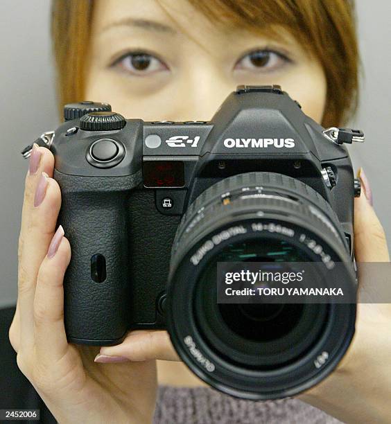 An employee of Japan's Olympus Optical Co., Ltd. Shows off its new 5.5-megapixel digital still camera "E-1" in Tokyo, 25 June 2003. The E-1 is the...