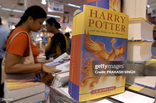 An Indian woman flicks through a book next to a display of the latest in J.K Rowlings Harry potter series, The Order of the Phoenix, at the Delhi...