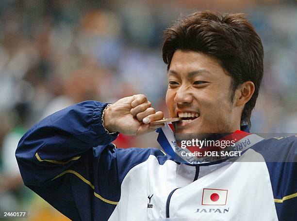 Men's 200m bronze medal winner Shingo Suetsugu of Japan bites his medal on the winner's podium, 29 August 2003, during the 9th IAAF World Athletics...