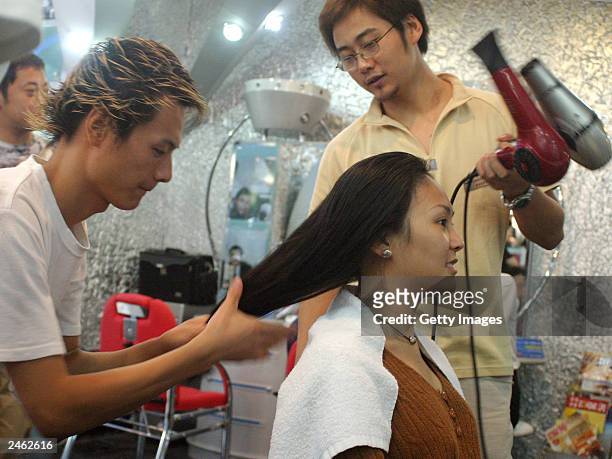 Lucy Hao a jewellery trader, has her hair blow-dried by her stylist September 4, 2003 in Beijing, China. Hao is keeping herself busy with shopping...