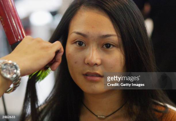 Lucy Hao a jewellery trader, sits as her stylist blow-dries her hair September 4, 2003 in Beijing, China. Hao is keeping herself busy with shopping...