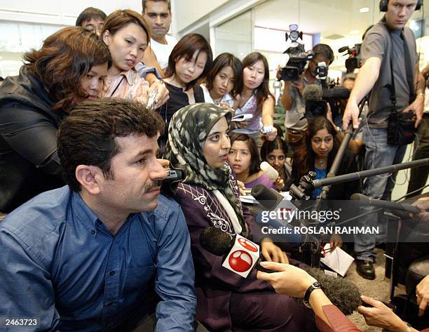 An Iranian couple are surrounded by reporters at the lobby of the Raffles Hospital while waiting for updates on the twin sisters laden and Laleh...