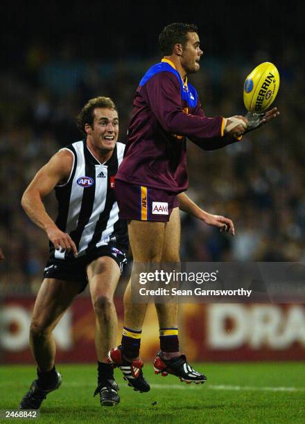 Ashley McGrath for Brisbane juggles the ball in front of Matthew Lokan for Collingwood during the AFL second qualifying final between the Collingwood...