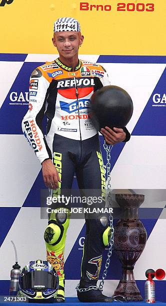 The winner Italian Valentino Rossi wearing a prisoners hat holds his ball and chain attached to him by his fans as he stands on the podium after...