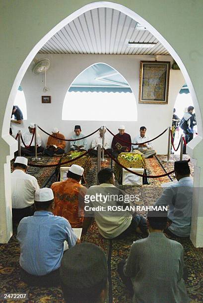 Faithfuls offer prayers in front of the coffins of Iranian twins Ladan and Laleh at Ba'Alwi Mosque in Singapore, 09 July 2003. The bodies of Ladan...