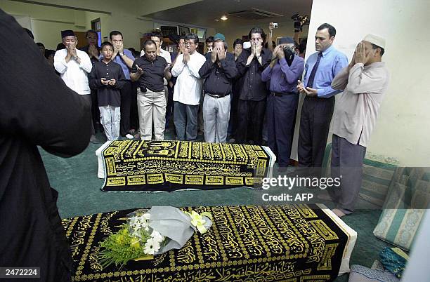 Faithfuls offer prayers infront of the coffins of Iranian twins Ladan and Laleh at Ba'Alwi Mosque in Singapore, 09 July 2003. The bodies of Ladan and...