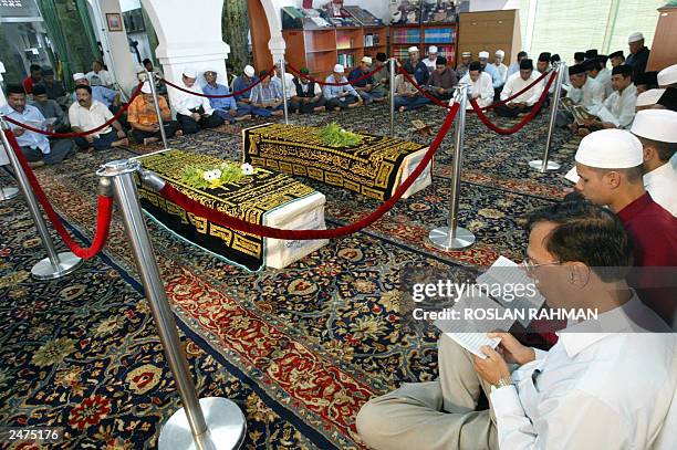 Faithfuls offer prayers in front of the coffins of Iranian twins Ladan and Laleh Bijaki at Ba'Alwi Mosque in Singapore, 09 July 2003. The bodies of...