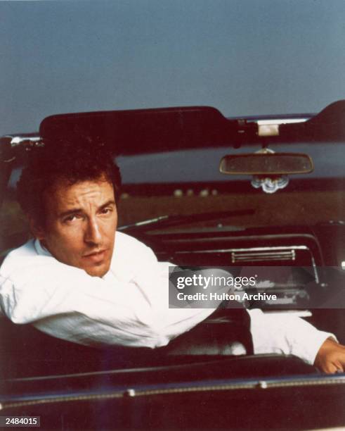 Portrait of American rock singer and songwriter Bruce Springsteen sitting in the driver's seat of a Cadillac convertible, circa 1987.