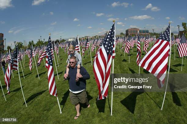 Jason Walsh and his 5-year-old son Payton walk among the 3,412 American flags in front of the Sandy City building in honor of those killed in the...