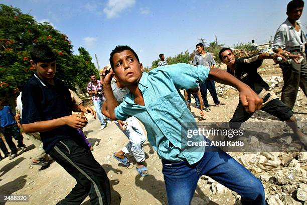 Palestinian youths throw stones towards Israeli soldiers at a nearby position where they guard the Israeli Jewish settlement of Kfar Darom, during...